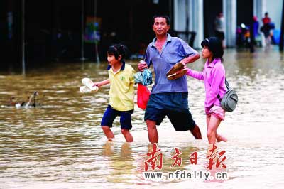 乐昌市政府前和街道被水浸,一位家长带着孩子涉水而行。　　谷立辉童铜韶朱裕超摄