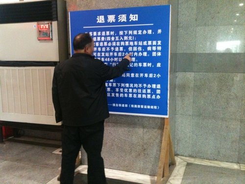 昨日，上海站，一位老人在认真研究退票新规。 李淑平 图